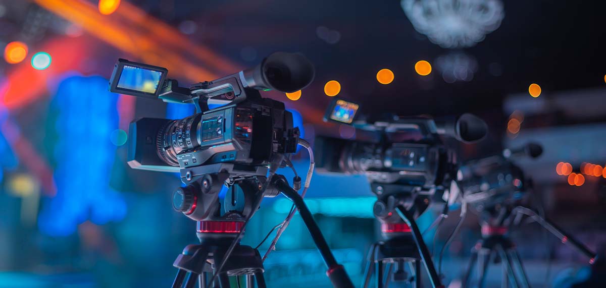 Camera operator on a tripod filming a live event