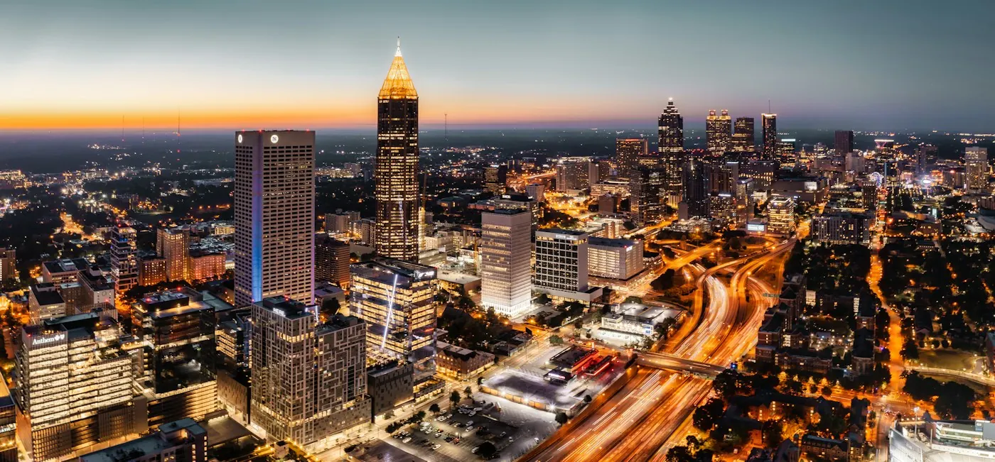 Atlanta skyline at dusk with illuminated towers and highway light trails