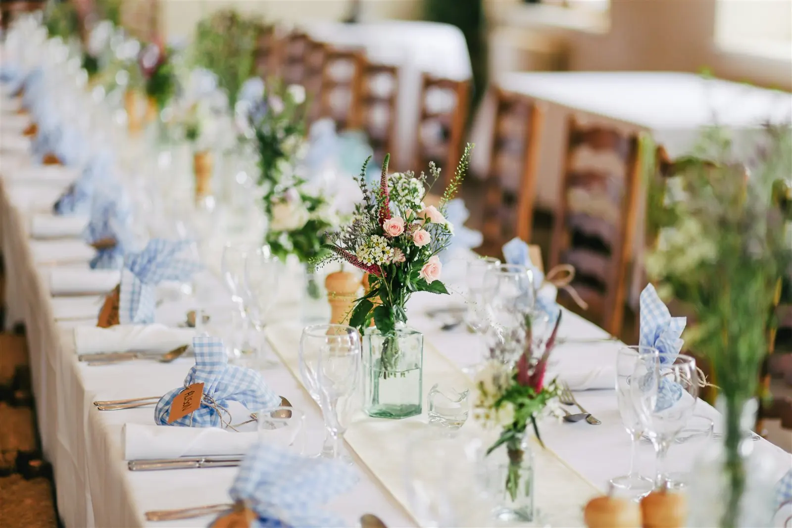 Floral arrangements and place settings along a reception table
