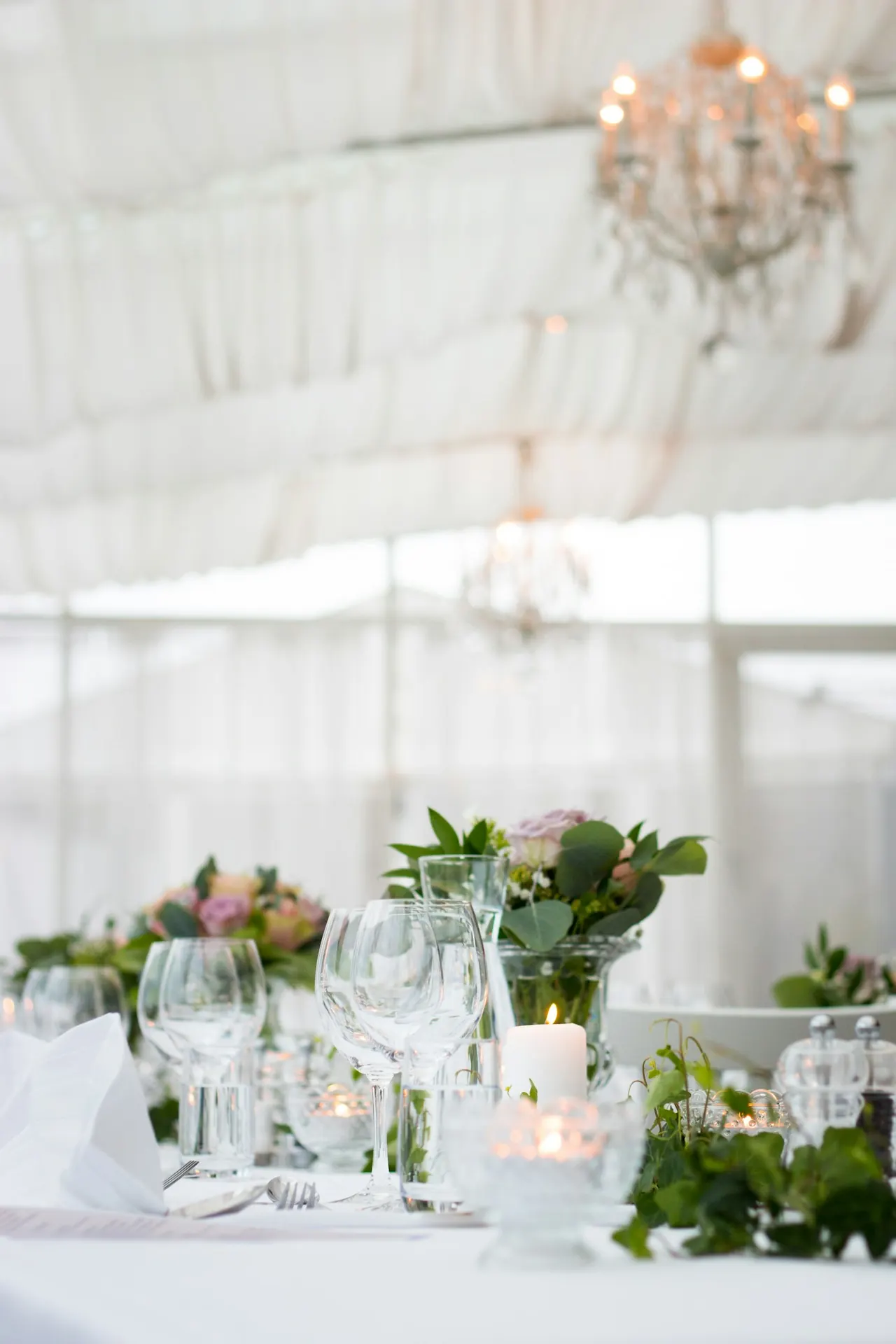 White reception table with fresh flowers and glassware