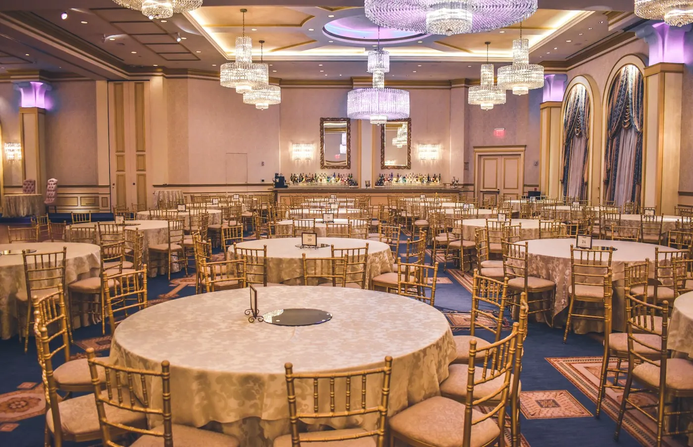 Elegant ballroom set with round tables and gold chairs