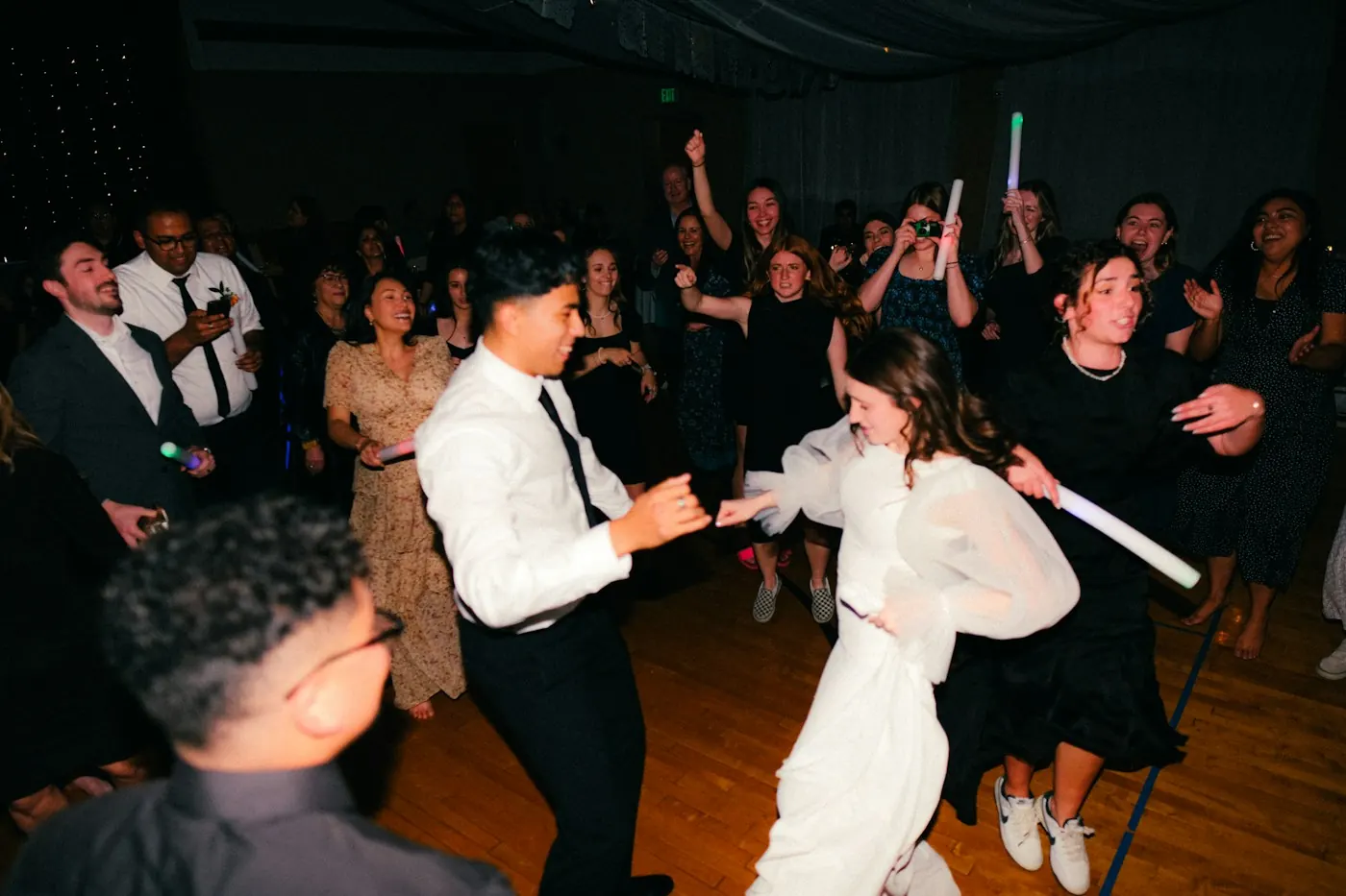 Couple dancing with guests at an evening wedding reception